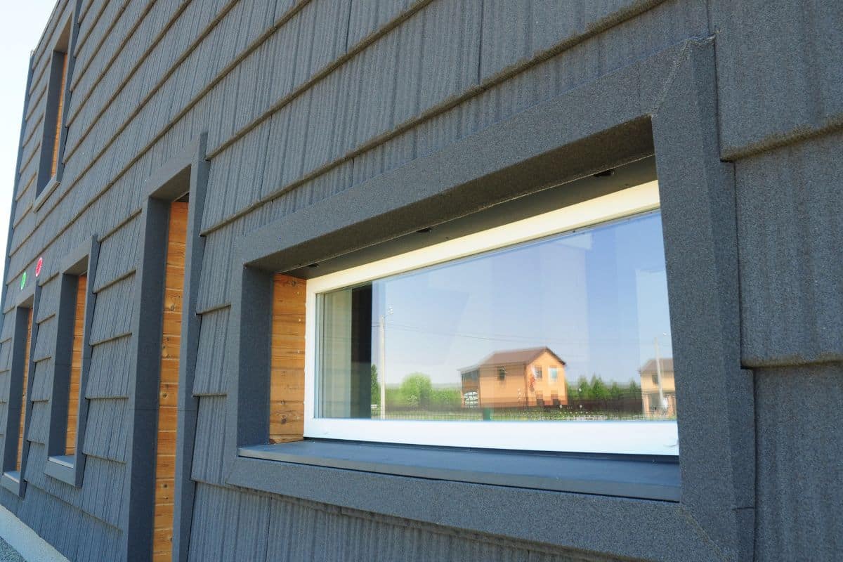 Finestra di una casa passiva con rivestimento in legno e grigio.