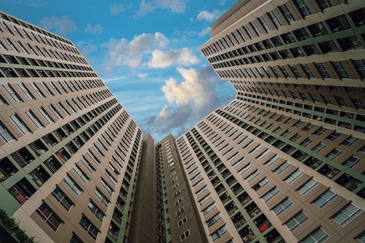 Grattacieli residenziali moderni con cielo blu e nuvole bianche.