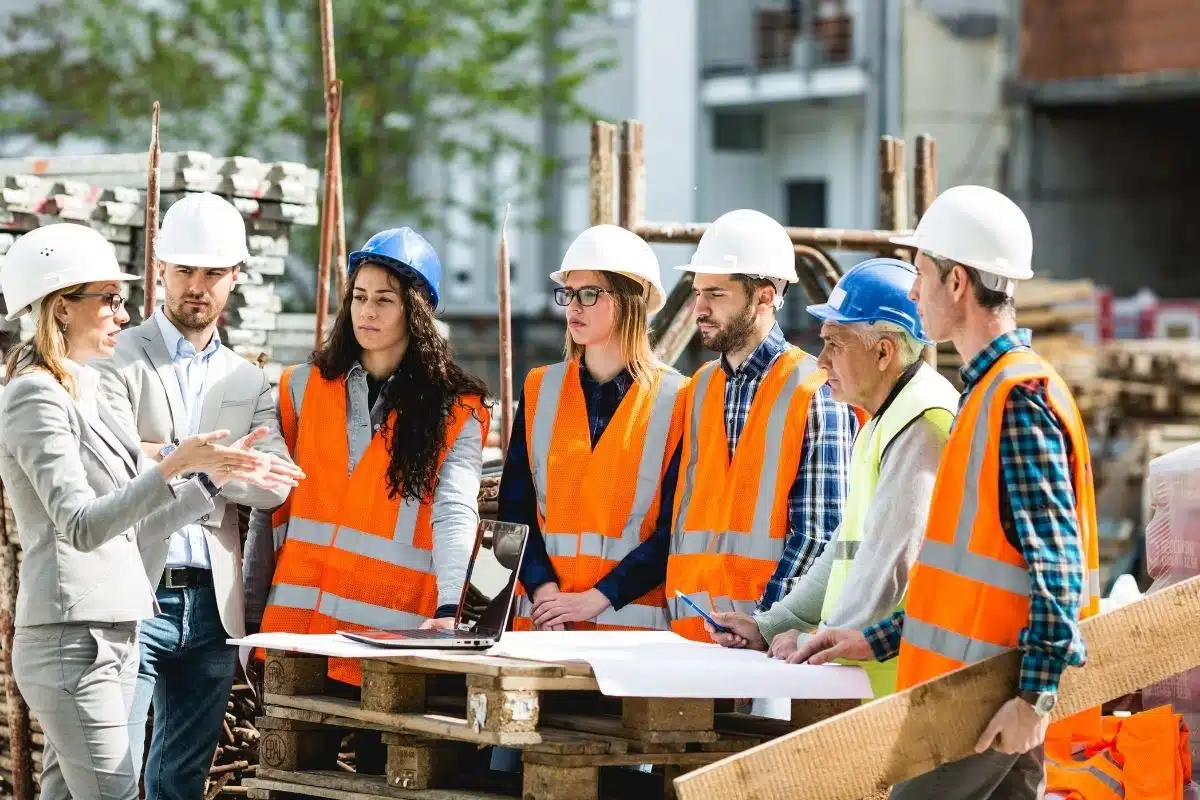 Ingegneri e operai in cantiere discutono di progetti edilizi.