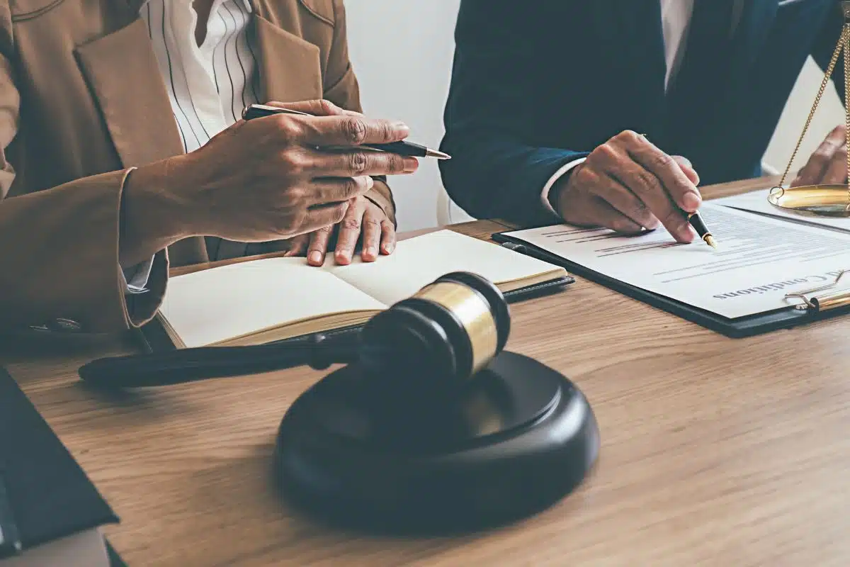 Due persone al tavolo, documento, penne e martello del giudice