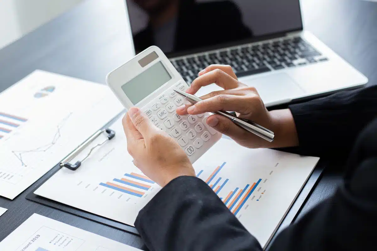 Persona al lavoro con calcolatrice e grafici, risparmio energetico.