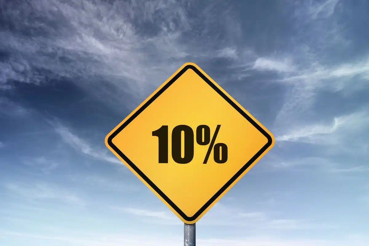 Cartello giallo con scritta "10%" su sfondo cielo azzurro.