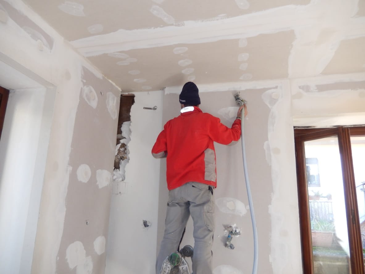 Coibentazione muri perimetrali: operaio al lavoro, isolamento termico interno, cappotto termico, ristrutturazione casa. Massimo comfort abitativo.