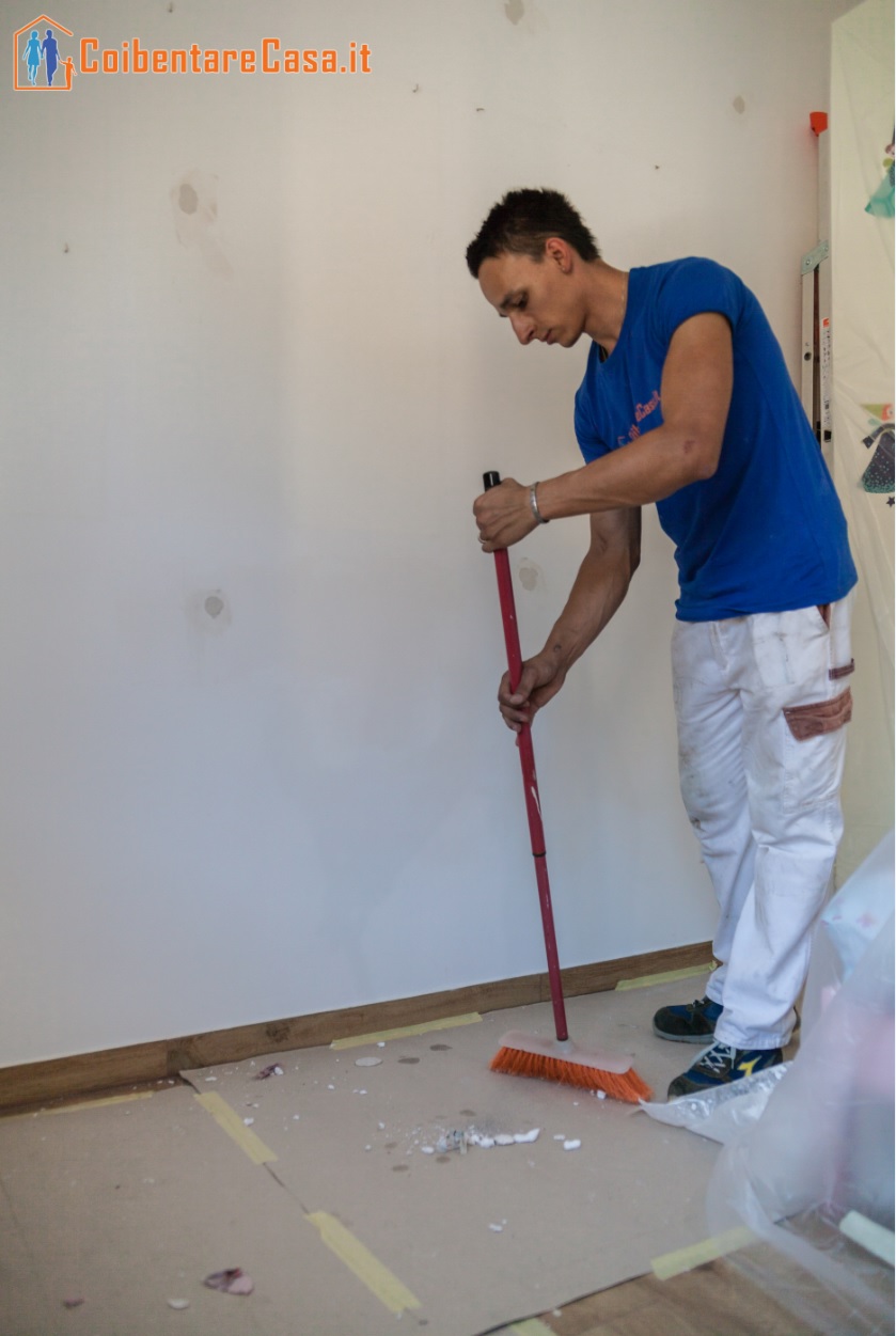 Uomo pulisce il pavimento con la scopa prima di togliere i cartoni. Preparazione post-lavoro, pulizia e ordine.